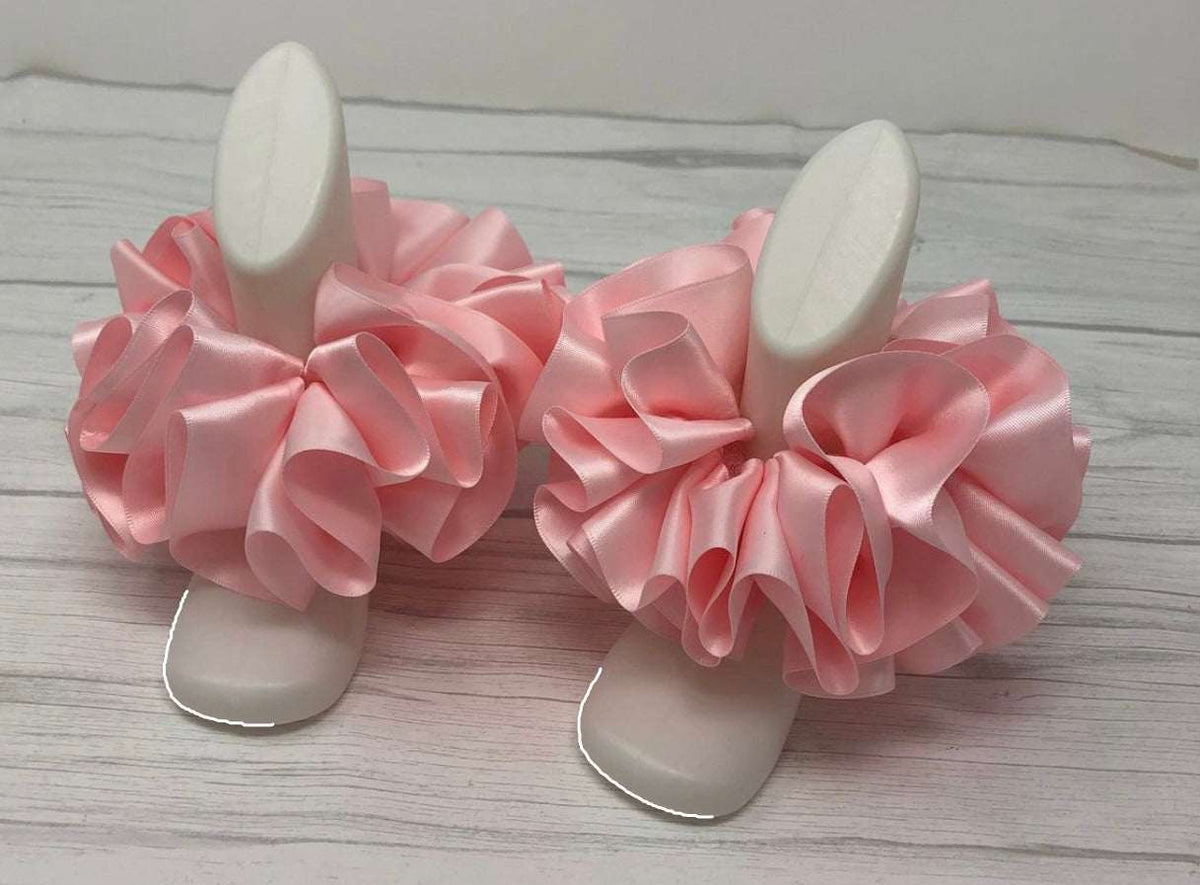 Elegant single color pink satin anklets displayed on white foot mannequins on wooden surface